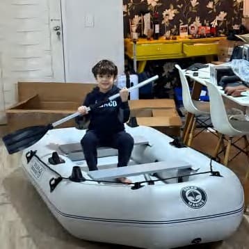 A child sitting in a grey Solar Marine inflatable boat with an oar